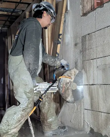Close up of a hand holding a saw cutting concrete